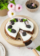 View from above. Piece of homemade chocolate cake with vanilla cream decorated with blackberry,...