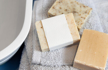 Soap bars with blank label on light grey towels near vessel sink in bathroom closeup, mockup