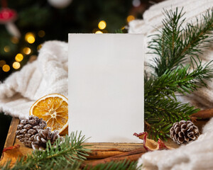 Blank card near pine cones, spices, white knitted sweater and fir twigs.  Christmas mockup