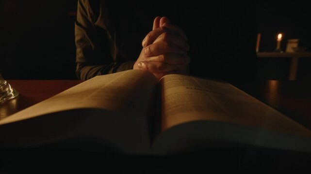 A believer is reading the Bible in the evening, researching the holy scripture in soft candle light, spiritual practice of young preacher, Middle shot, High quality 4k footage