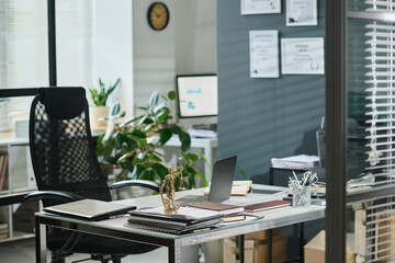 Part of spacious modern office with workplace of notary or lawyer with laptop surrounded by documents and other stationary