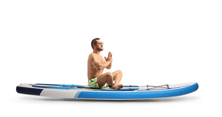 Full length profile shot of a man practicing meditation on a SUP board