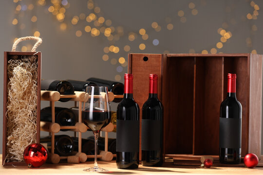 Bottles of wine, glass, wooden gift boxes, barrel corks and red Christmas balls on table