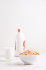 bowl of corn granola with milk, fresh raspberries, blueberries . milk in a jug and a glass  on white wooden board for healthy breakfast