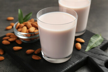 Glasses of almond milk and almonds on grey table