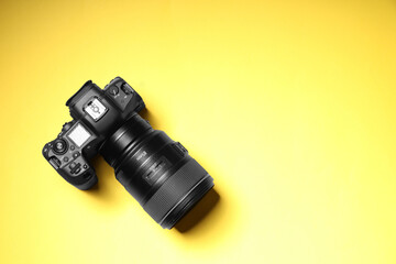 One modern photo camera on yellow background, top view. Space for text