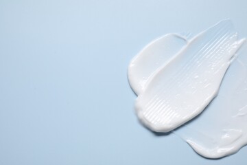 Face cream on light blue background, top view. Space for text