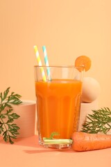 Fresh carrot juice in glass and vegetable on coral background
