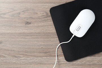 Computer mouse with mousepad on wooden desk, top view. Space for text