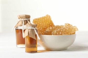 Natural honey tincture and sweet honeycombs on white wooden table