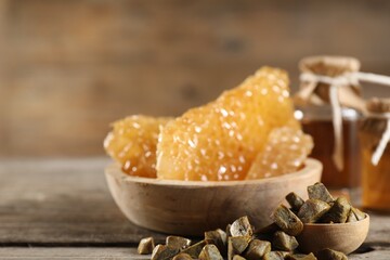 Natural honey tincture, propolis granules and sweet honeycombs on wooden table, closeup