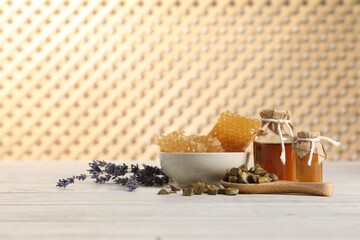 Natural honey tincture, lavender, propolis granules and sweet honeycombs on white wooden table,...