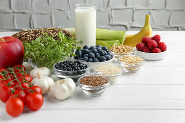 Different fresh products on white wooden table, space for text. Source of prebiotics