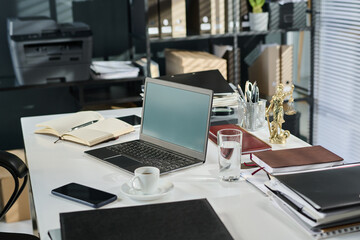 Desk with laptop of lawyer, open notepad with working notes, glass of water, cup of coffee or tea, mobile phone and other supplies