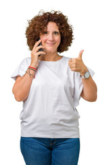 Middle ager senior woman talking on smartphone over isolated background happy with big smile doing ok sign, thumb up with fingers, excellent sign