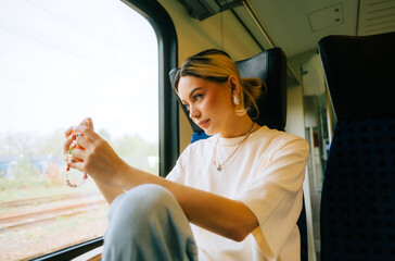 Naklejka premium Attractive caucasian woman using a smartphone in regional train. Young beautiful woman using public transportation.