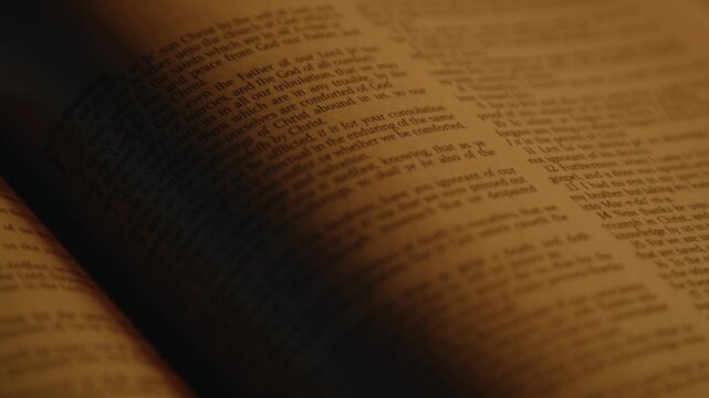 Bible printed text in soft candle light, one page of holy scripture, New Testament, Close up, High quality 4k footage