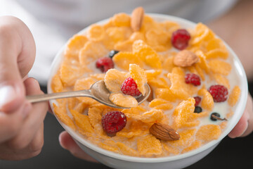 Man eating tasty cornflakes with milk in bowl, closeup