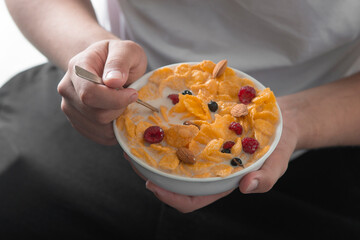 Man eating tasty cornflakes with milk in bowl, closeup