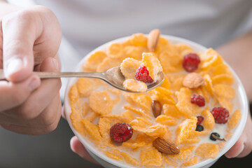 Man eating tasty cornflakes with milk in bowl, closeup