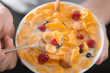 Man eating tasty cornflakes with milk in bowl, closeup