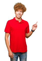 Young handsome man with afro hair wearing red t-shirt with a big smile on face, pointing with hand and finger to the side looking at the camera.