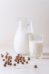 Milk in a glass and chocolate balls on a light background.