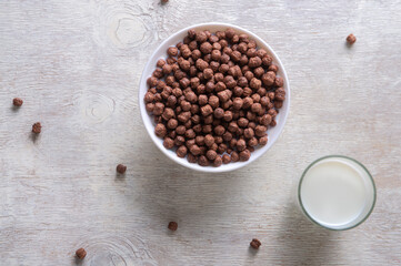 Milk in a glass and chocolate balls on a light background.