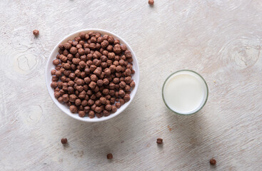 Milk in a glass and chocolate balls on a light background.