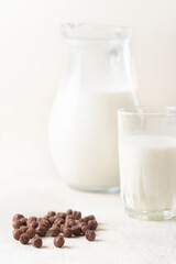 Milk in a glass and chocolate balls on a light background.