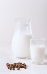 Milk in a glass and chocolate balls on a light background.