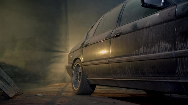 dusty old youngtimer car is in a service station or garage. Beautiful luxury retro car with yellow light from the window.