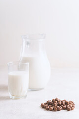 Milk in a glass and chocolate balls on a light background.