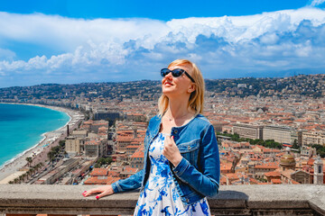 A woman enjoys a coastal city view on a sunny day, embracing the beauty and leisure of the moment. Nice, France.