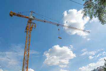 Equipment for the construction and lifting of bulky goods with construction materials. The tower crane is attached to the boom with a load secured with steel cables. Construction equipment.