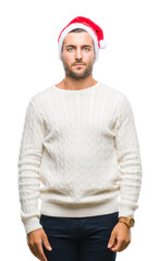 Young handsome man wearing santa claus hat over isolated background with serious expression on face. Simple and natural looking at the camera.