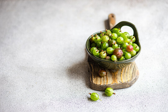 Close-up of a bowl of fresh organic gooseberries on a wooden chopping board - Powered by Adobe