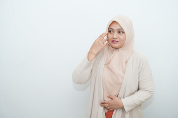 Portrait of a beautiful young Asian Muslim woman wearing a hijab being photographed in a studio