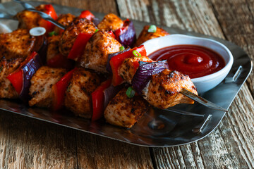 Chicken skewers kebabs with bell peppers and  onions on wooden board, close up