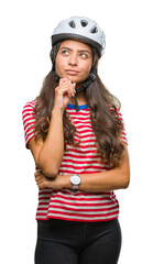 Young arab cyclist woman wearing safety helmet over isolated background with hand on chin thinking about question, pensive expression. Smiling with thoughtful face. Doubt concept.