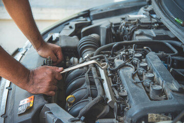 Close up Mechanic man hands repairing car auto repair shop uses jack change tyre. Man hands fixing Shock absorber machinery vehicle mechanical service. Vehicle Car overhaul maintenance engineer