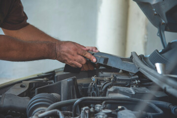 Fototapeta premium Close up Car Mechanic man hands repairing car auto repair shop. Man hands fixing machinery vehicle mechanical service. open vehicle hood checking up auto mobile. Vehicle Car maintenance engineer.