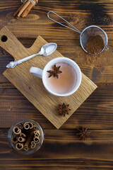 Cocoa drink in the white cup, cinnamon and anise on the wooden background. Top view. Close-up.