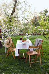 Stylish table setting with beautiful spring flowers, tea and croissants in garden