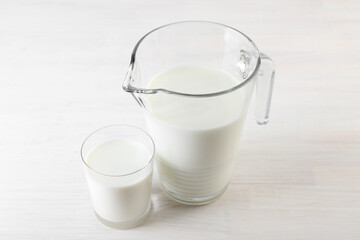 Jug and glass of fresh milk on wooden table