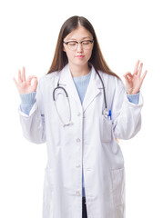 Young Chinese doctor woman over isolated background relax and smiling with eyes closed doing meditation gesture with fingers. Yoga concept.