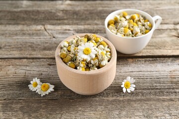 Dry and fresh chamomile flowers on wooden table