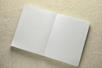 Book with Braille text on beige textured table, top view. Education and leisure for blind people