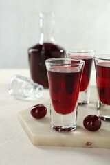 Delicious cherry liqueur and berries on white table