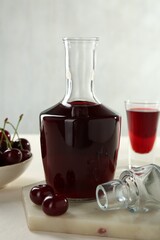 Delicious cherry liqueur and berries on white table